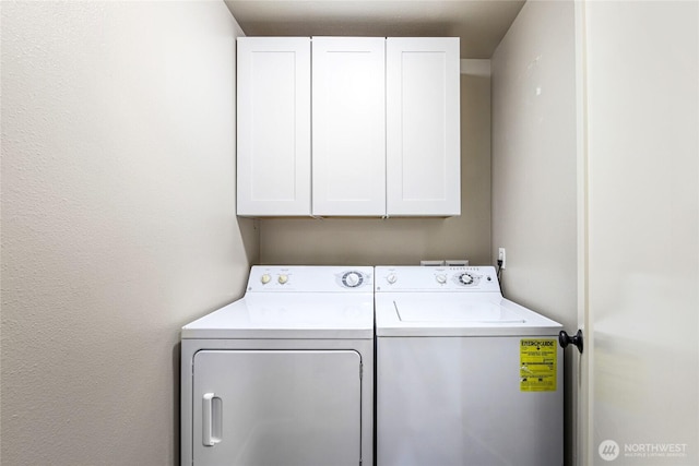 clothes washing area featuring washing machine and clothes dryer and cabinet space