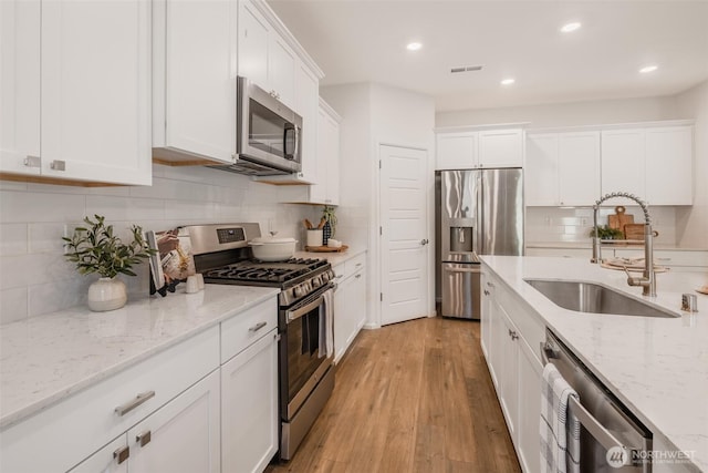 33140 Glacier Ave SE, Black Diamond, WA 98010 - kitchen with light wood-type flooring, backsplash, a sink, white cabinets, and appliances with stainless steel finishes