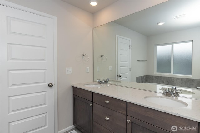 bathroom featuring double vanity, visible vents, a sink, and recessed lighting