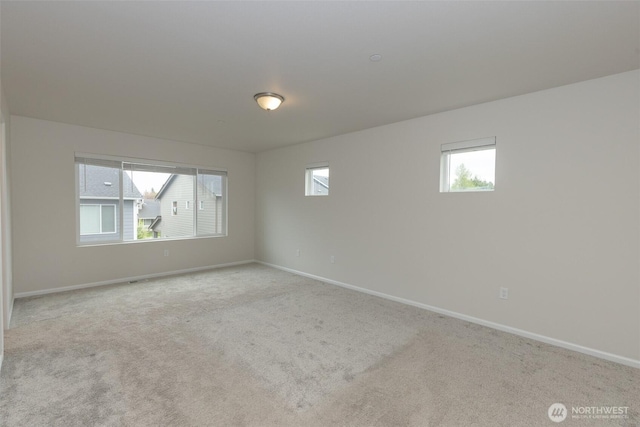 carpeted spare room featuring baseboards and a healthy amount of sunlight
