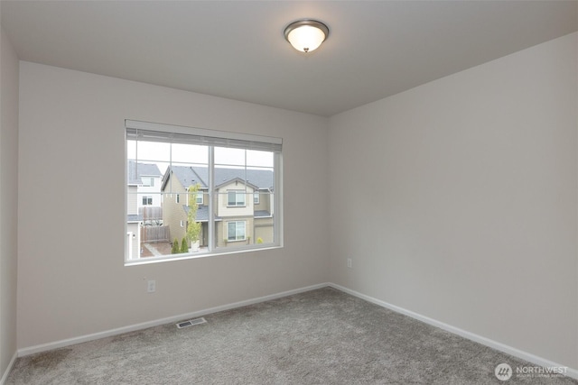 empty room featuring baseboards, visible vents, and carpet