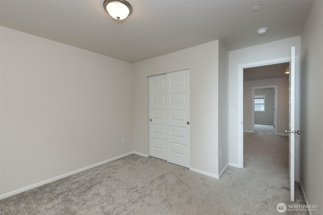 unfurnished bedroom with a closet, baseboards, and carpet flooring