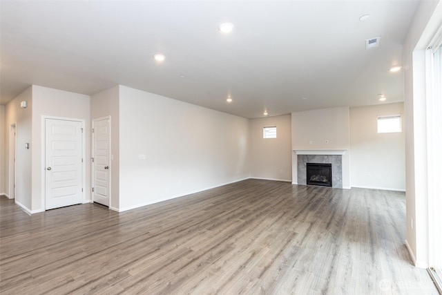 unfurnished living room with baseboards, recessed lighting, wood finished floors, and a tile fireplace
