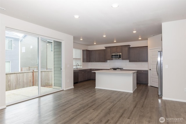 kitchen with a kitchen island, dark wood-style flooring, dark brown cabinets, light countertops, and stainless steel appliances