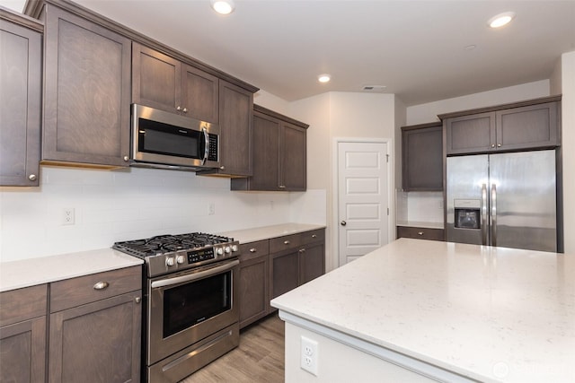 kitchen with visible vents, tasteful backsplash, dark brown cabinets, stainless steel appliances, and light wood-style flooring