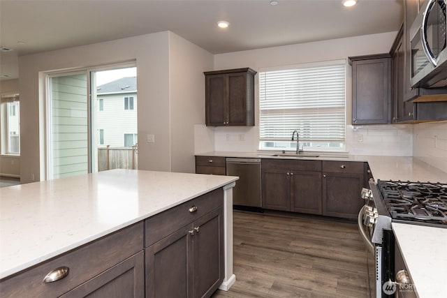 kitchen with a sink, appliances with stainless steel finishes, dark brown cabinets, and tasteful backsplash