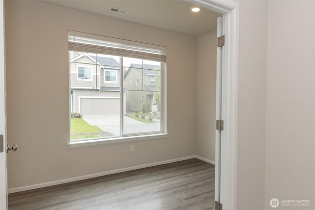 unfurnished room with baseboards, visible vents, a wealth of natural light, and wood finished floors
