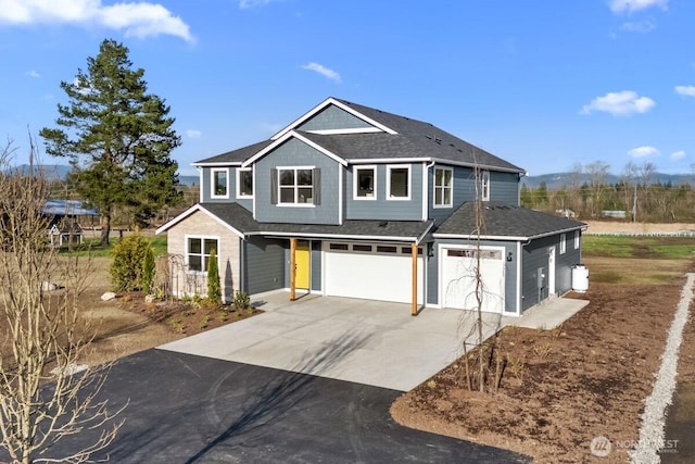 craftsman-style house featuring an attached garage, driveway, and roof with shingles