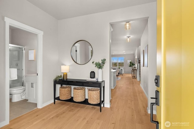 hallway with light wood-type flooring and baseboards