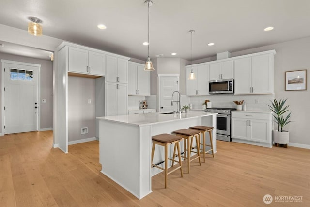 kitchen with baseboards, appliances with stainless steel finishes, tasteful backsplash, and a sink