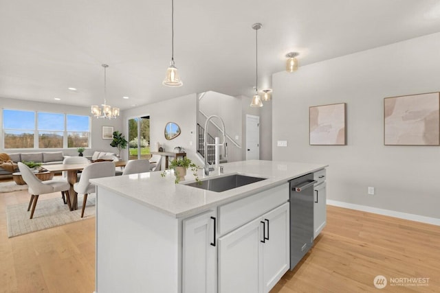 kitchen with light wood-type flooring, open floor plan, dishwasher, and a sink