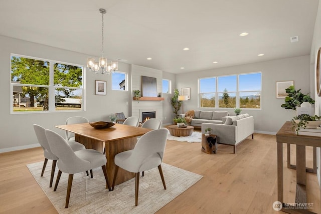 dining room featuring an inviting chandelier, baseboards, a fireplace, and recessed lighting