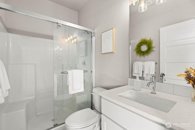bathroom featuring toilet, vanity, and a stall shower