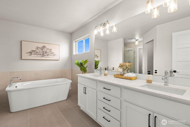 bathroom with tile patterned floors, a sink, double vanity, and tile walls