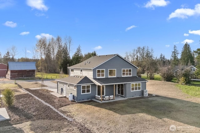 rear view of house featuring a shingled roof and driveway