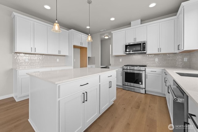 kitchen with white cabinets, appliances with stainless steel finishes, tasteful backsplash, and light wood finished floors