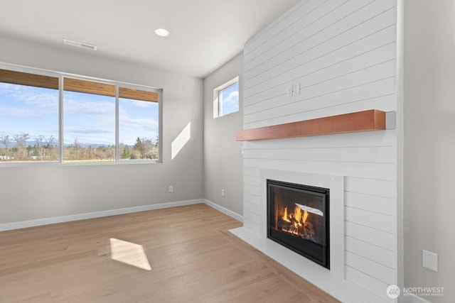 unfurnished living room featuring wood finished floors, a large fireplace, baseboards, visible vents, and recessed lighting