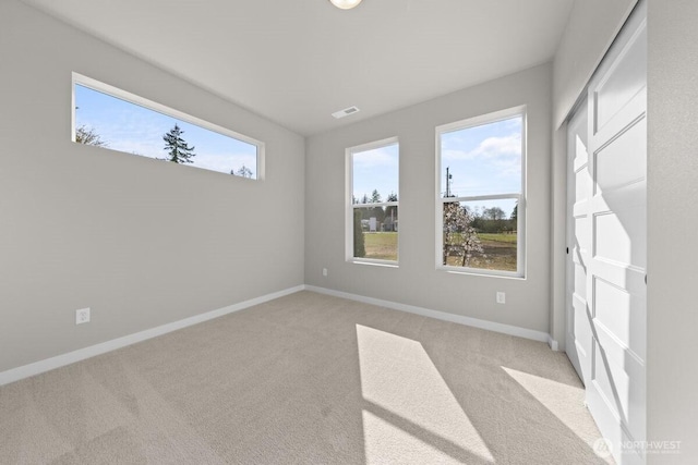 spare room with visible vents, baseboards, and light colored carpet