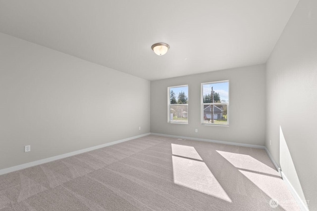 spare room featuring baseboards and light colored carpet