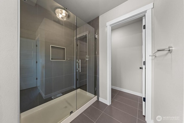 full bathroom with a shower stall, baseboards, and tile patterned flooring