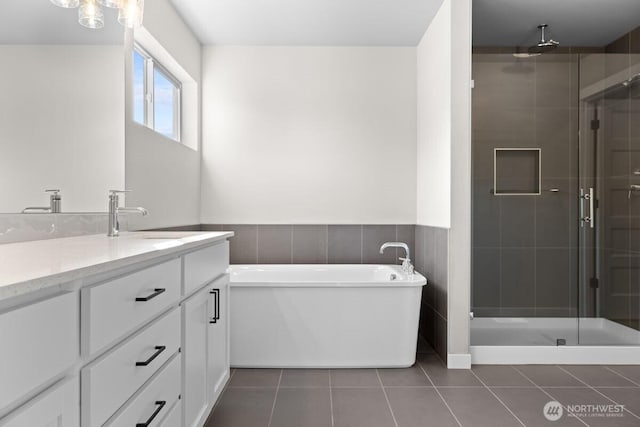 full bathroom featuring tile patterned floors, a stall shower, wainscoting, vanity, and a freestanding bath
