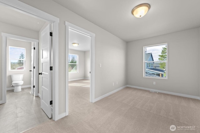 spare room with light colored carpet, baseboards, and visible vents