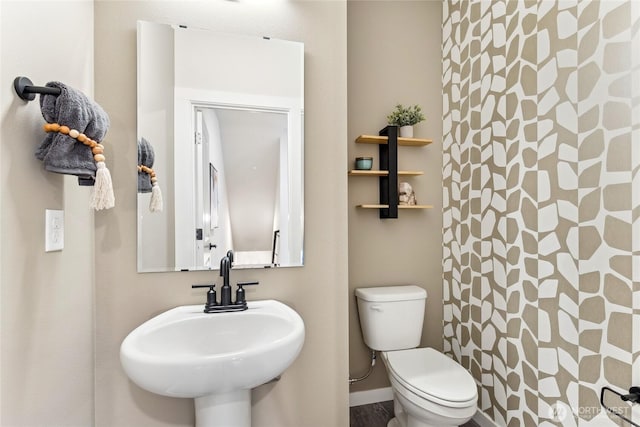 bathroom featuring a sink, a shower with curtain, toilet, and baseboards