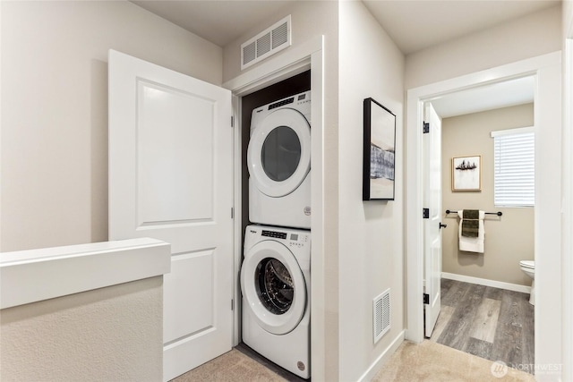 laundry area with laundry area, stacked washer and dryer, baseboards, and visible vents