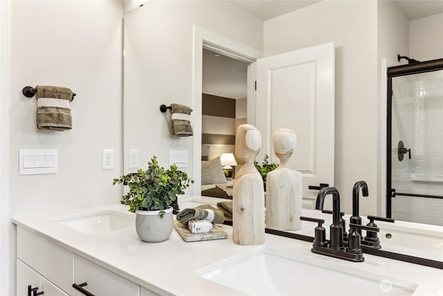 bathroom with double vanity, a shower stall, and a sink