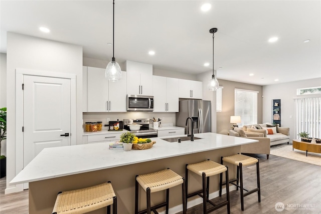 kitchen featuring stainless steel appliances, a breakfast bar area, an island with sink, and a sink
