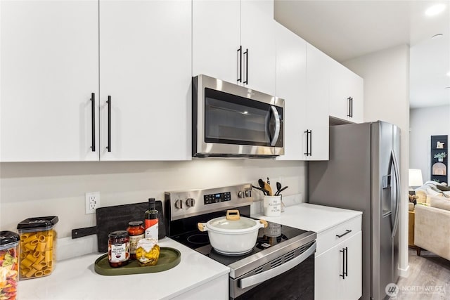 kitchen featuring wood finished floors, light countertops, white cabinets, and appliances with stainless steel finishes