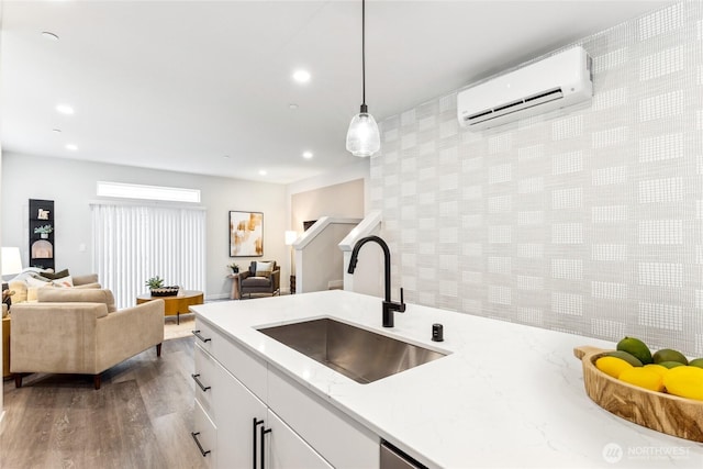 kitchen featuring a wall mounted air conditioner, open floor plan, recessed lighting, and a sink
