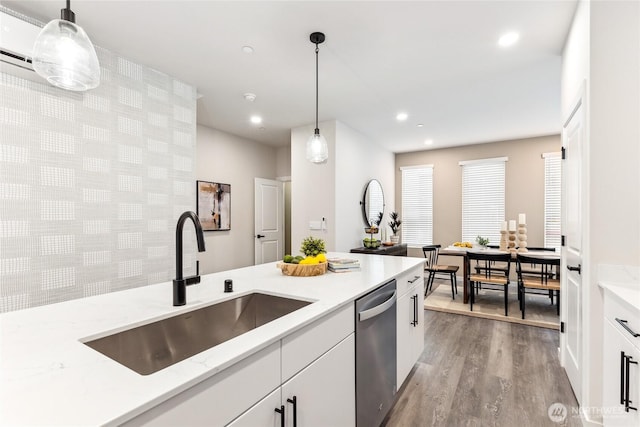 kitchen featuring dishwasher, light stone counters, a sink, wood finished floors, and white cabinets
