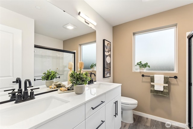 bathroom with a sink, toilet, an enclosed shower, and wood finished floors