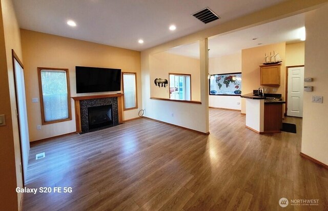 unfurnished living room with visible vents, a tile fireplace, baseboards, wood finished floors, and recessed lighting