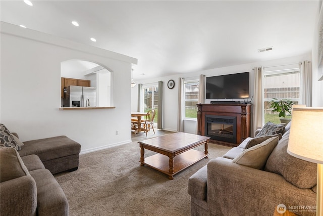 living area featuring visible vents, baseboards, carpet floors, recessed lighting, and a glass covered fireplace
