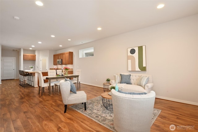living area featuring baseboards, wood finished floors, and recessed lighting