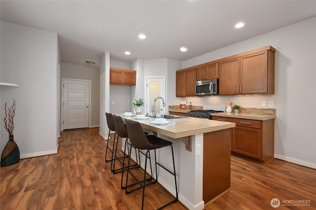 kitchen with brown cabinets, range with gas stovetop, a sink, and stainless steel microwave