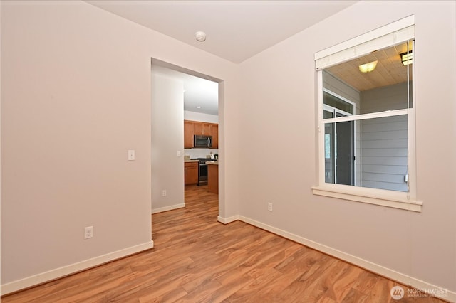 spare room with baseboards and light wood-style floors
