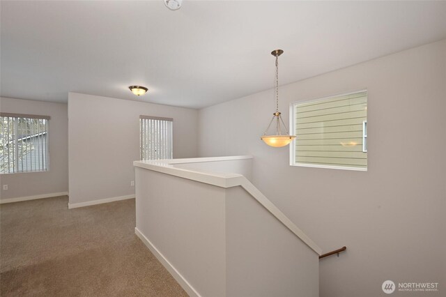 corridor featuring an upstairs landing, carpet, and baseboards