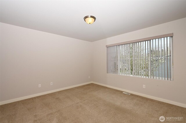 empty room with light colored carpet, visible vents, and baseboards
