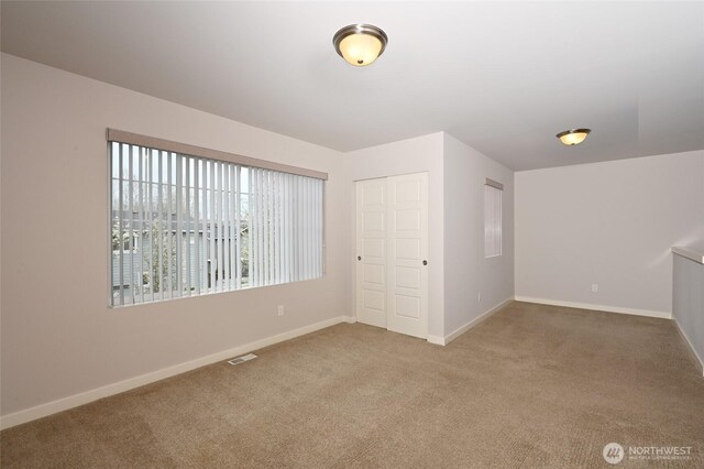 unfurnished room featuring baseboards, visible vents, and carpet