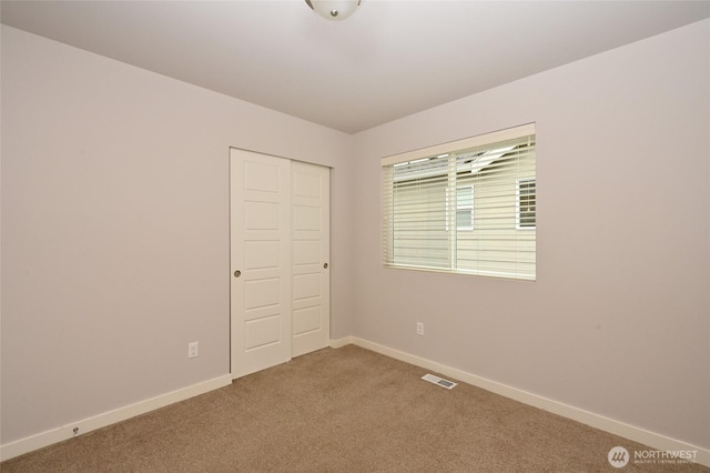 unfurnished bedroom with baseboards, carpet flooring, visible vents, and a closet