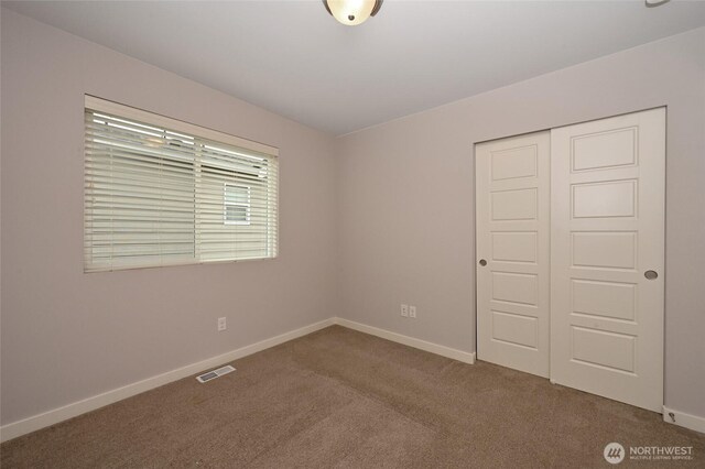 unfurnished bedroom with baseboards, visible vents, a closet, and carpet floors