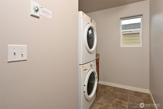 washroom with stacked washer and dryer, baseboards, and laundry area