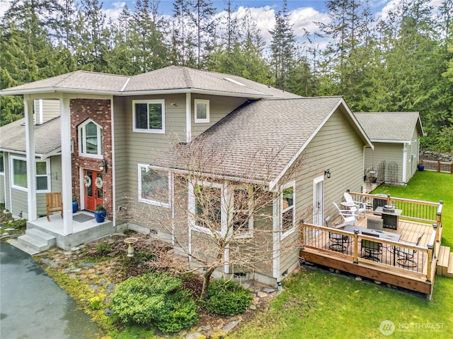 view of front of property featuring a shingled roof, a front yard, and a wooden deck