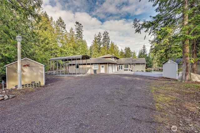 view of front of house with driveway, an outbuilding, and a storage unit