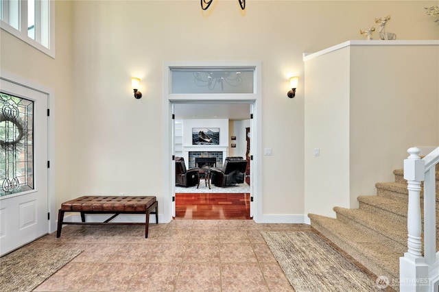 tiled entryway featuring a high ceiling, a fireplace, and stairs