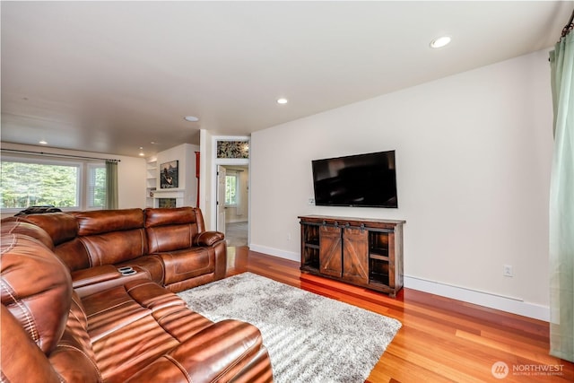 living room featuring recessed lighting, baseboards, a fireplace, and wood finished floors