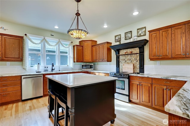 kitchen featuring a sink, decorative light fixtures, appliances with stainless steel finishes, and light wood-style floors